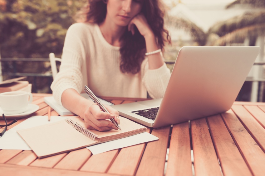 woman-writing-and-working-on-laptop-outdoors
