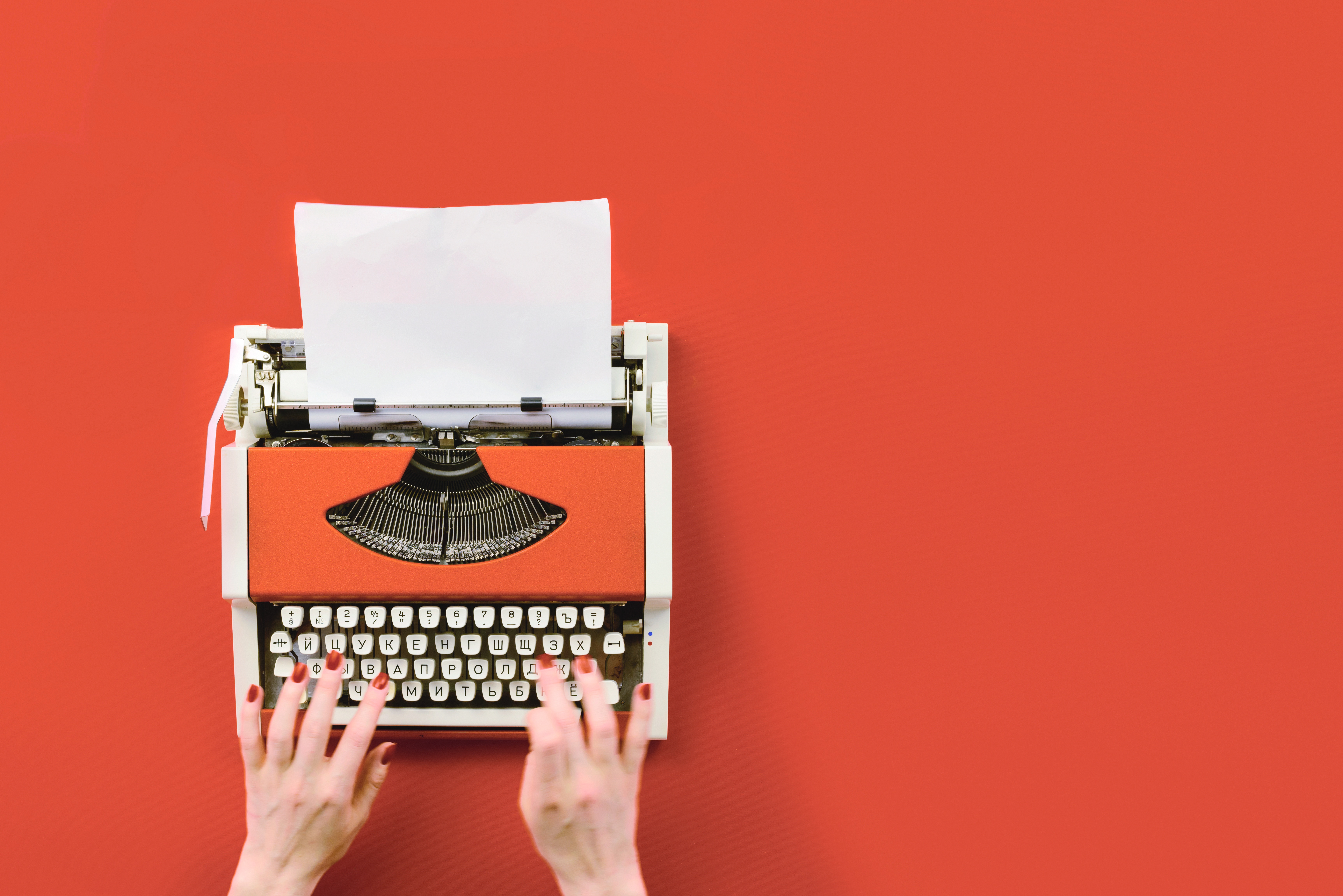 hands-typing-on-typewriter-orange-background